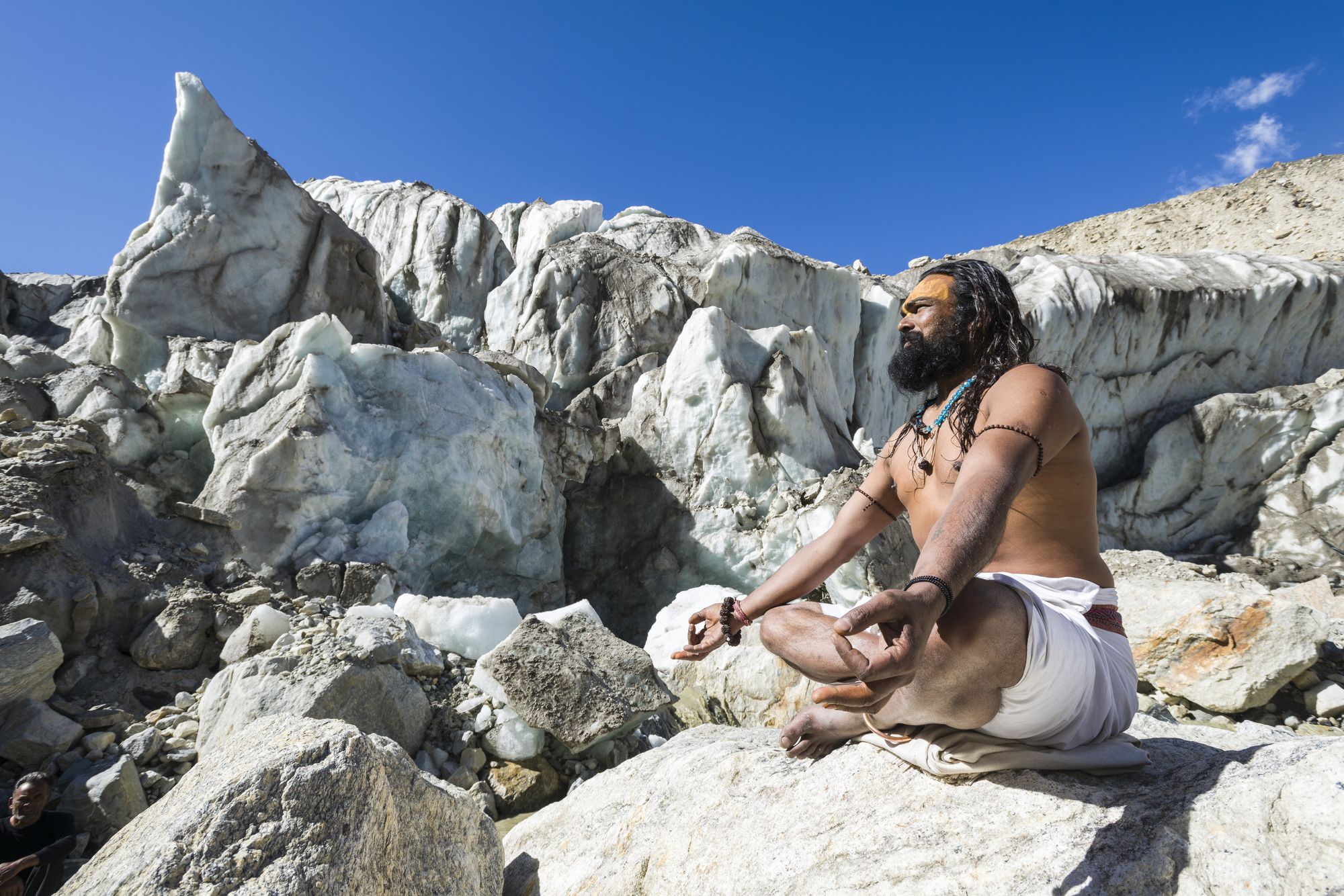 Un sadhu seduto su una roccia presso Gaumukh, la sorgente del fiume sacro Gange, Uttarakhand