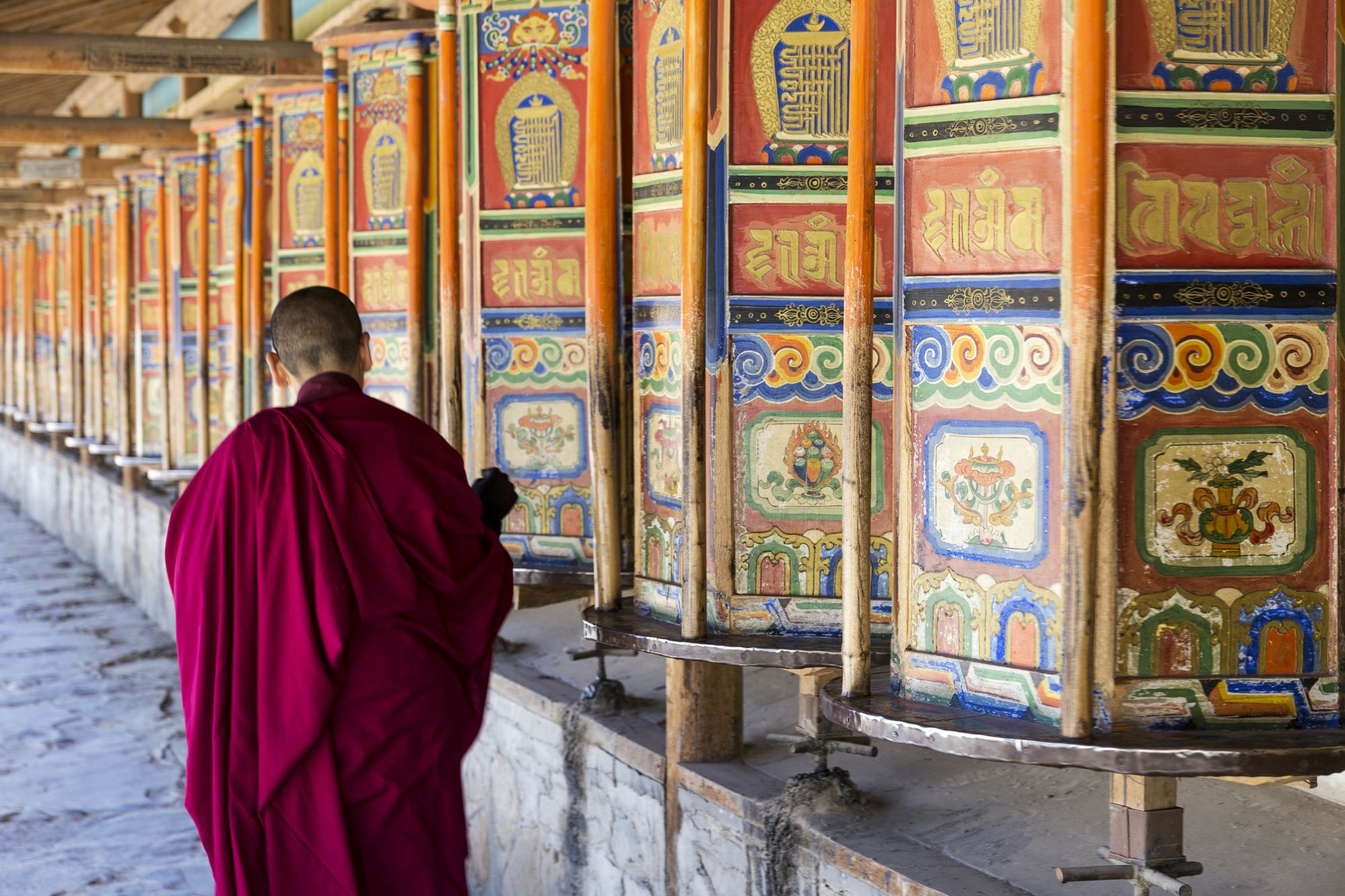 Un monaco gira le grandi, colorate ruote di preghiera nel monastero di Labrang a Xiahe. © owngarden/Getty Images