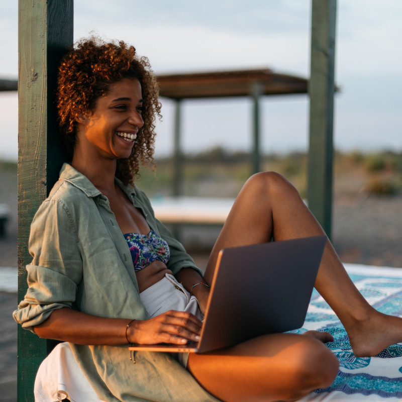 Ragazza che lavora al pc sulla spiaggia