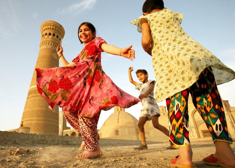 Bambini giocano e ballano davanti all'antica città di Bukhara, Uzbekistan. ©Chekunov Aleksandr/Shutterstock