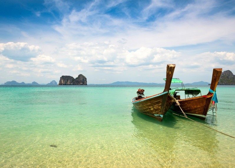 Due longtail boat adagiate su una spiaggia con il Limestone Rock sullo sfondo a Trang, Thailandia. ©Sunphol Sorakul/Getty Images