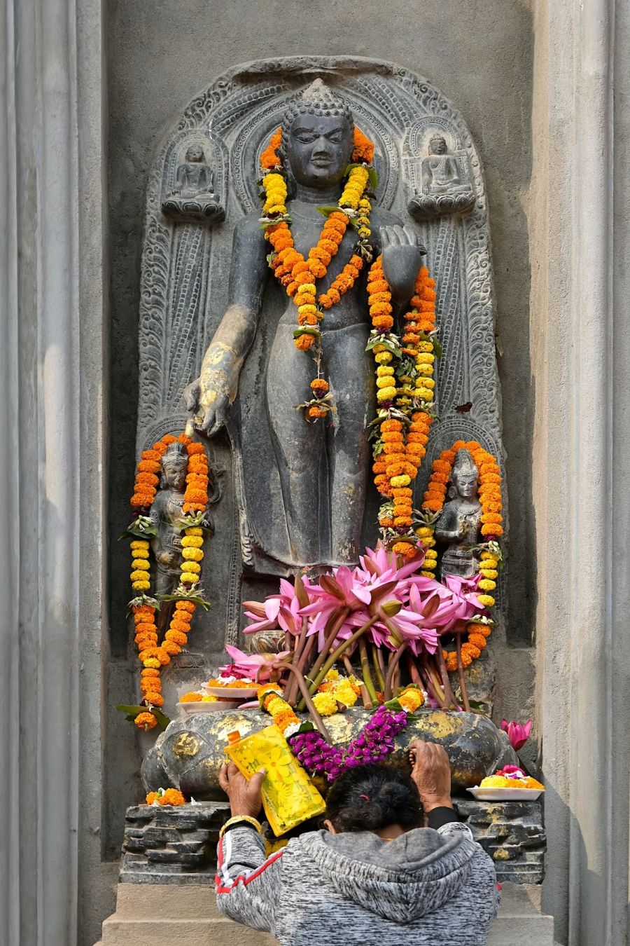 Un devoto davanti a una statua del Buddha in posizione eretta nel Tempio Mahabodhi, Bodhgaya, Bihar. pacceka/Shutterstock