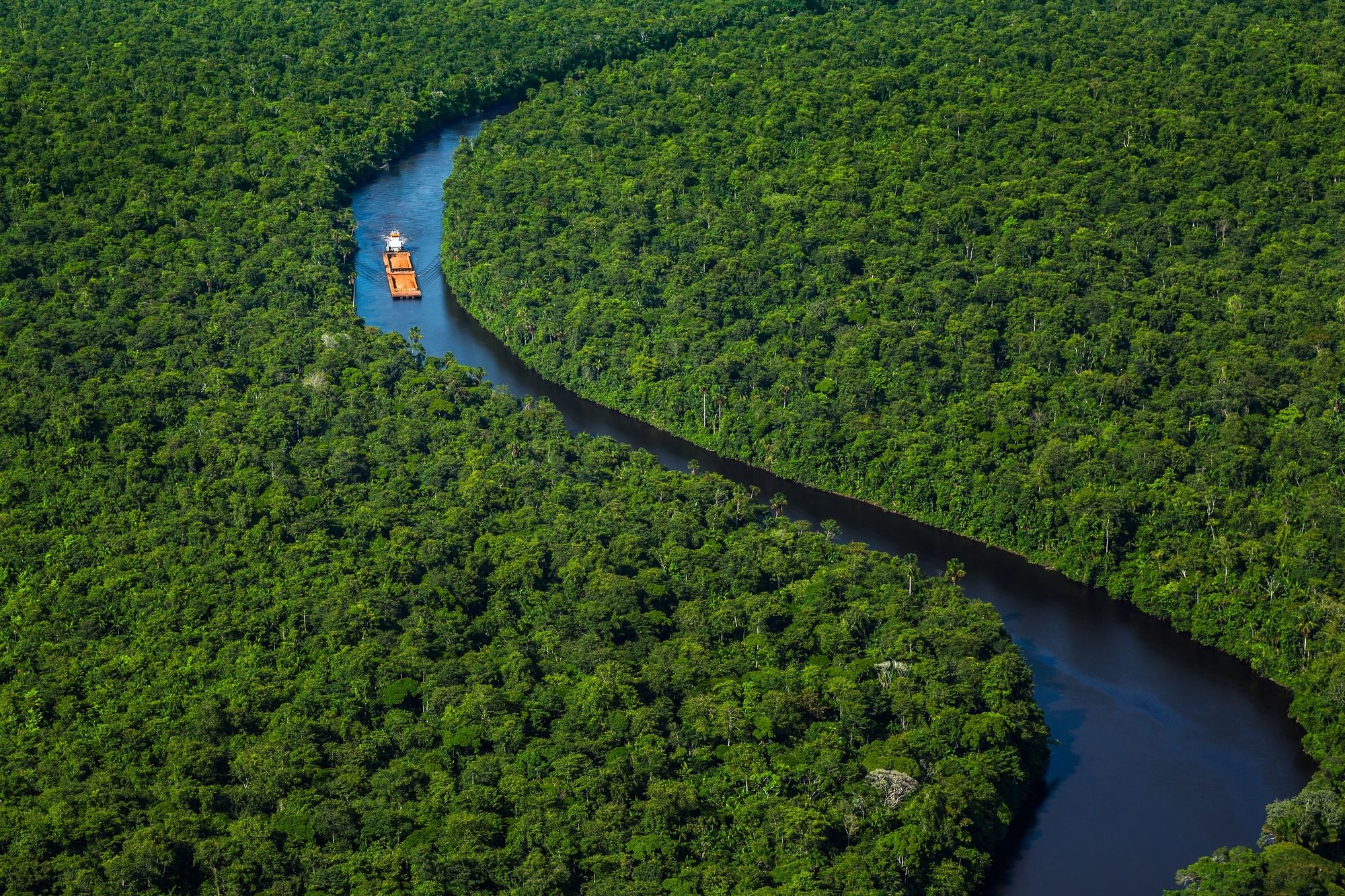 Una nave trasporta il suo carico lungo il fiume della foresta pluviale ©Karel Donk/500px