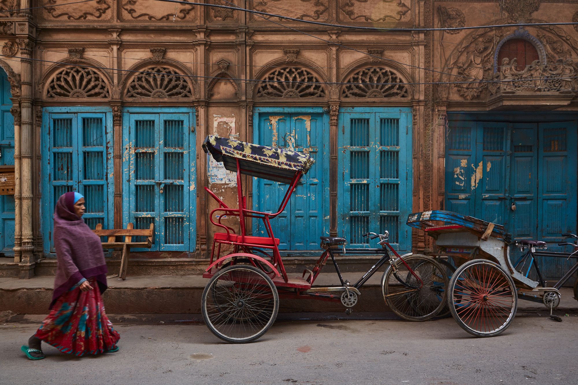 Donna in abiti tradizionali che cammina su una strada colorata con biciclette a Delhi, ©Eddie Huibonhoa/500px