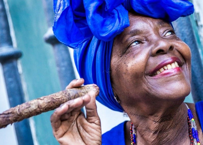 Una signora fuma un sigaro sulla porta di casa, Avana, Cuba.©ESB Professional/Shutterstock