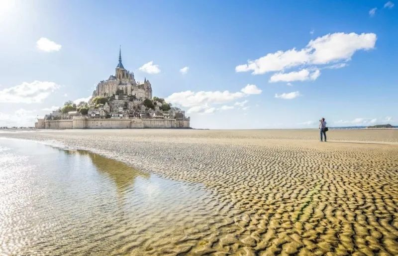 Il Mont-Saint-Michel e la sua baia con la bassa marea, un luogo emblematico della Normandia accessibile senza auto. canadastock - Shutterstock